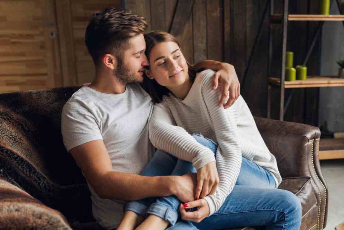 young smiling couple sitting couch home casual outfit