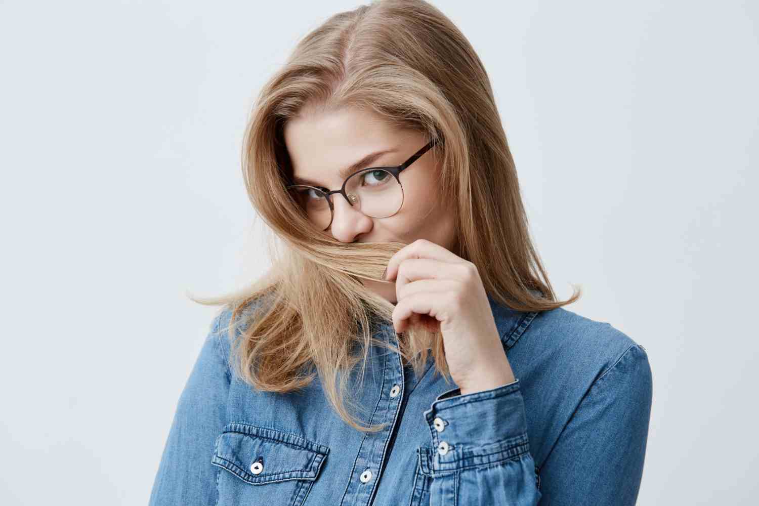 youth happiness concept beautiful caucasian teenage girl denim shirt looking camera with appeal playing with blonde hair young woman with perfect healthy skin stylish eyewear
